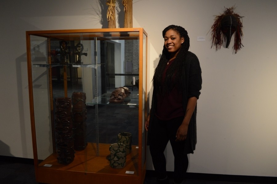 RAW artist Dejeonge Reese standing next to a display of her artwork. 