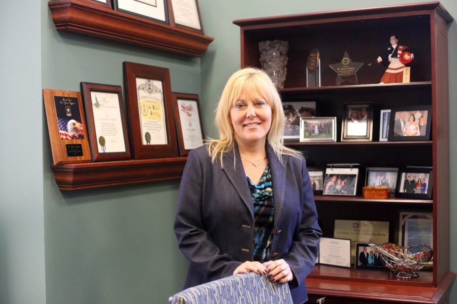 President Dawn Lindsay stands before her many awards, accolades, and mementos.