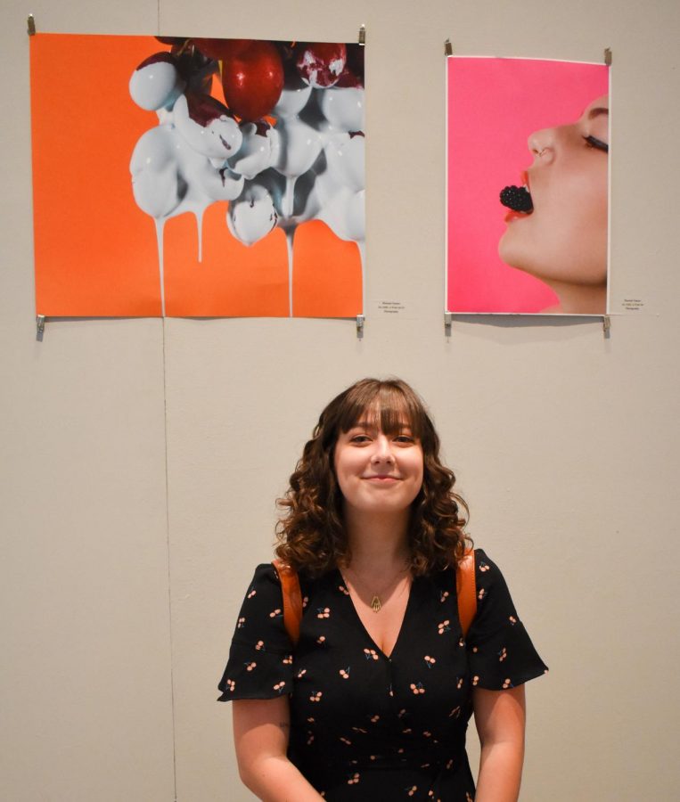 Hannah Tenner kneels in front of her photographs, Sex Sells: A Fruit Ad parts one (right) and two.