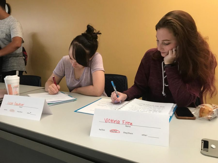 First-year students Lizzie Gauthier and Victoria Fitez take notes in Dr. Rachelle Tannenbaum’s psychology class. Tannenbaum uses name cards during her classes to display students’ preferred pronouns. 