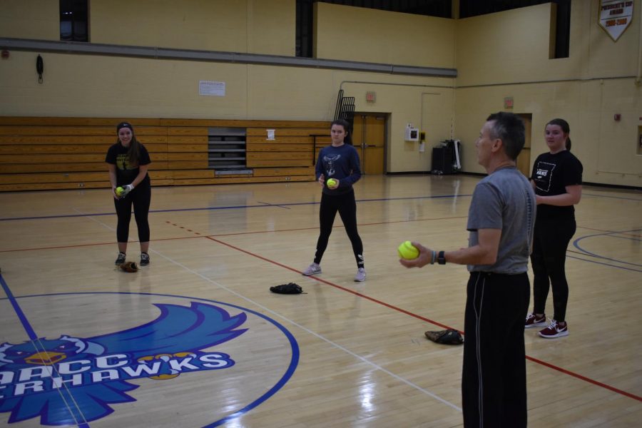 Softball head coach Guy Klingensmith talks to his team before starting drills in the gym.  