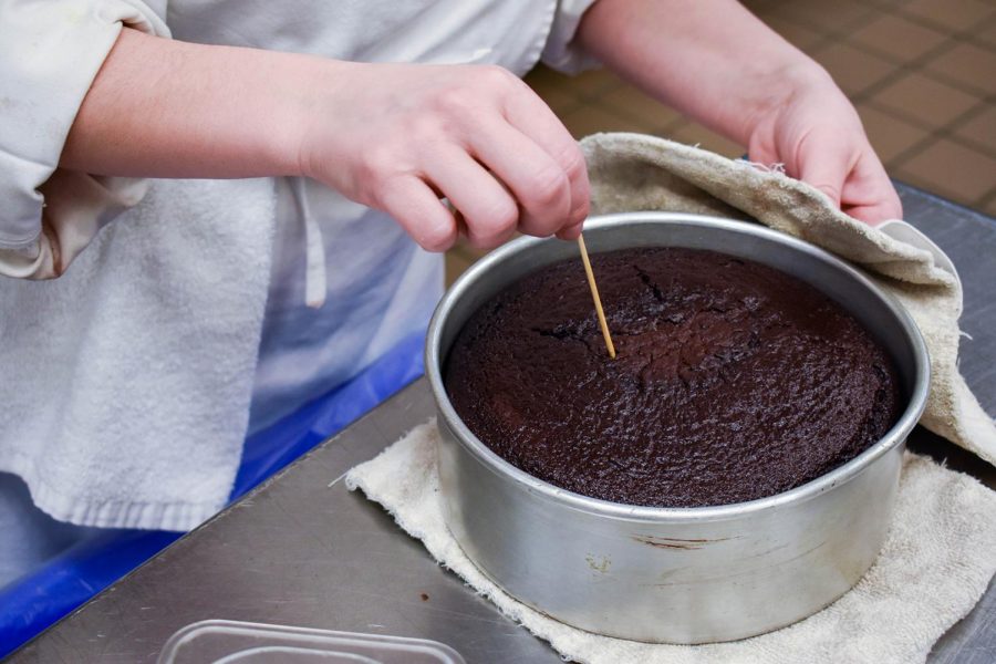 Thea Baumann, baking and pastry arts student, tests a cake with a toothpick to see if it's fully baked.