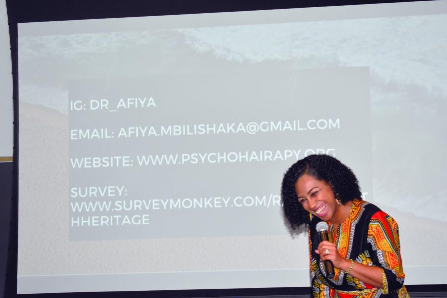 Psychologist Afiya Mbilishaka styles clients’ hair while she counsels them.