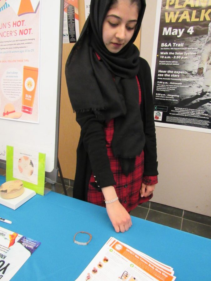 Lahiba+Ijaz%2C+a+first-year+business+administration+student%2C+demonstrates+how+to+use+a+special+UV+bracelet.+