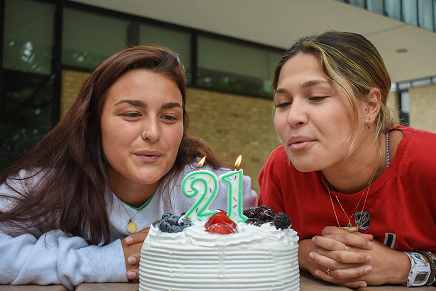 First-year nursing students Allie Riecke (left) and Kara Kishis blow out birthday candles on the Quad.