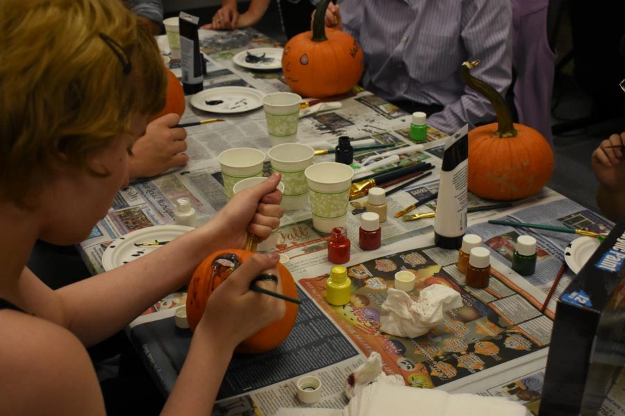 Students paint pumpkins with members from the Entrepreneurs Club. 