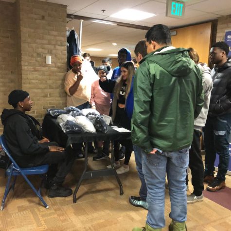 Students surround first-year business management and marketing student Josiah Parker, who sells his merchandise at a table during the Best of Business Trade Show.