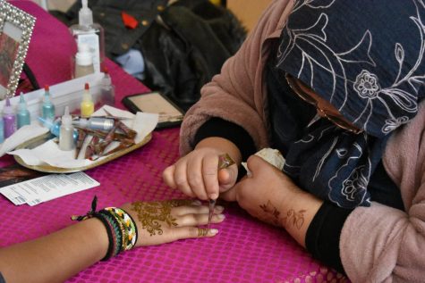 Henna artist Marcela Faruqui applies the design to a student's hand.