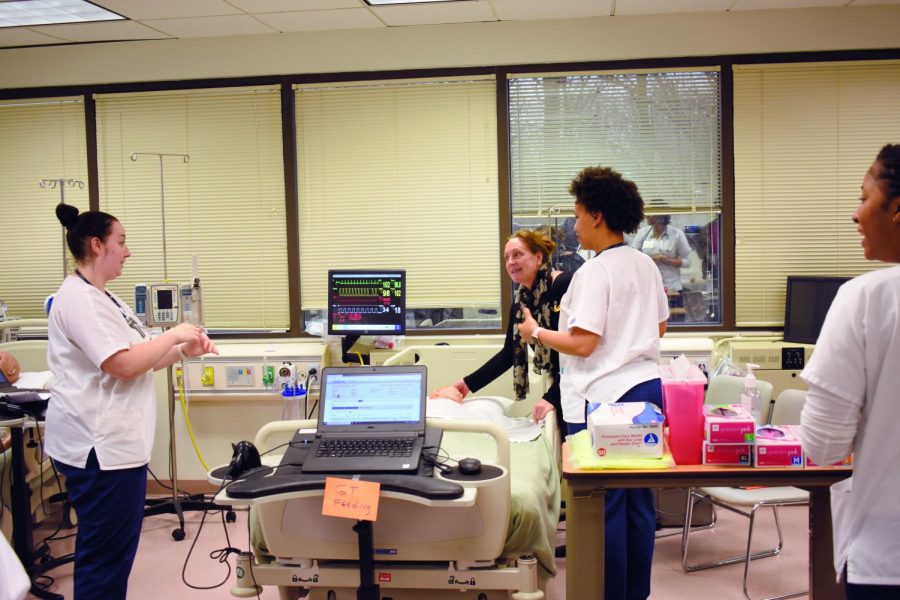 In one of her performances as an actor in Nursing Department lab simulations, Cindy Huebler (back) pretends to be a mother worried about her child.