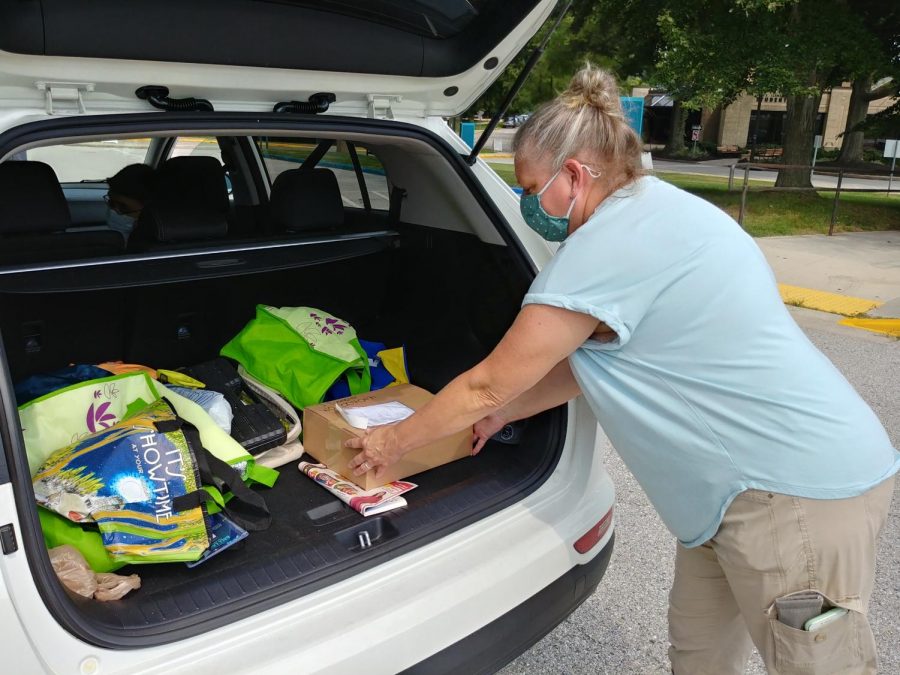 Health and Fitness Assistant Mary Moorer loads a curbside order from the AACC Bookstore in the back of a student’s car.