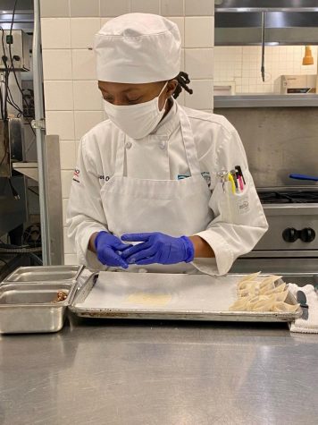 Culinary student Jeanette Pesseh wears a mask and gloves as she cooks for a class on campus.