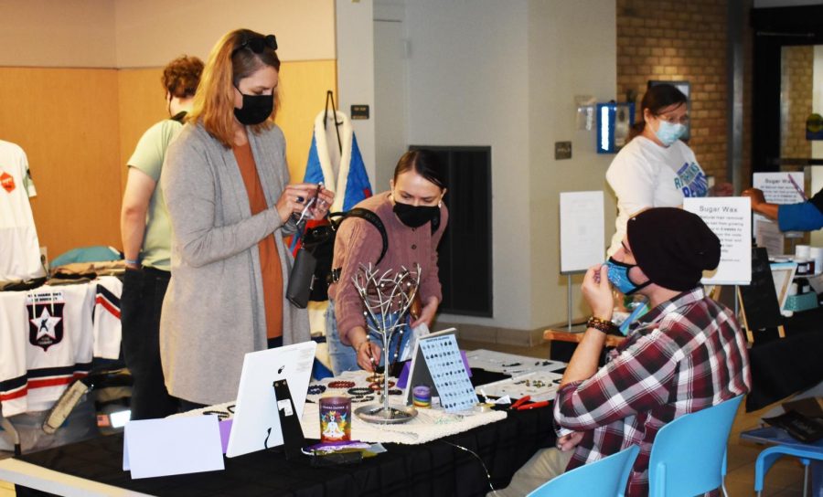 Business student Audrey Wais (middle) visits HawkTrade last week while Allison Baumbusch of the office of Strategic Communications makes a purchase from a student entrepreneur.