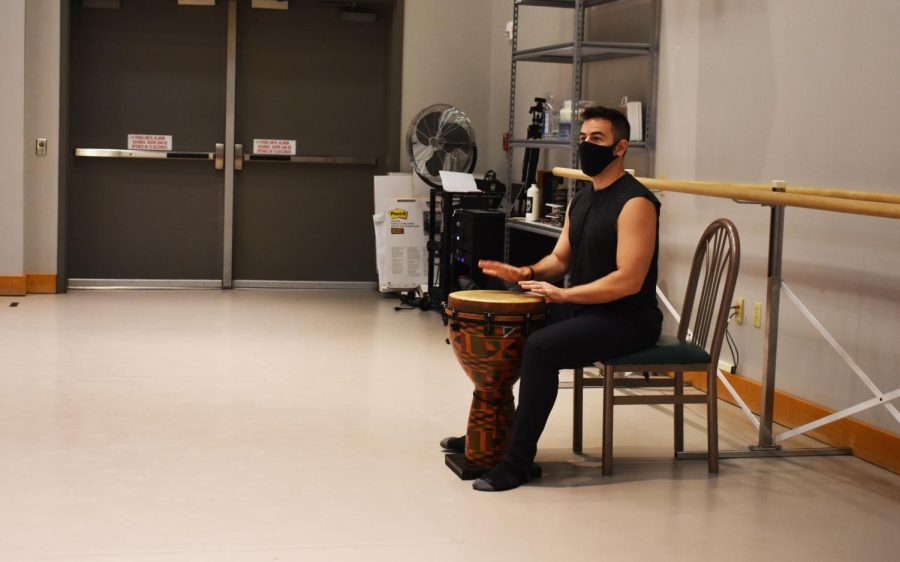 Dance professor playing a drum while sitting in a chair.