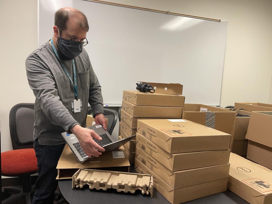 Student assistant supervisor Corey Allender unboxes loaner laptops.