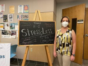 massage therapy professor Heather Langley poses next to chalkboard advertising the stress less event