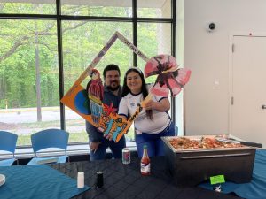 People pose in a themed frame behind a table of Latin of food.