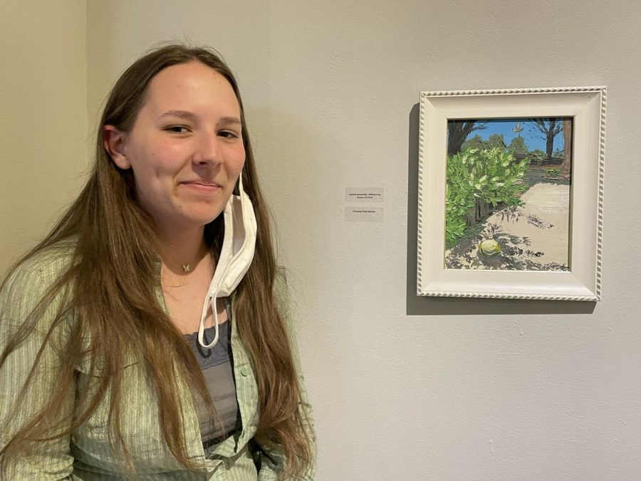 First-year digital art and design student Tabitha Broomfield  poses with her painting at the Student Art Exhibition on campus.