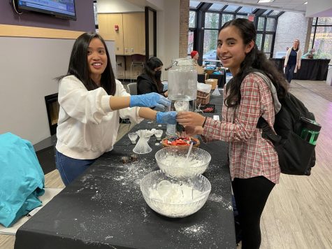 Third-year public student Marie Butiu teaches first-year environmental science student Parinaaz Patel how to make a stress ball by putting cornstarch and water into a balloon.