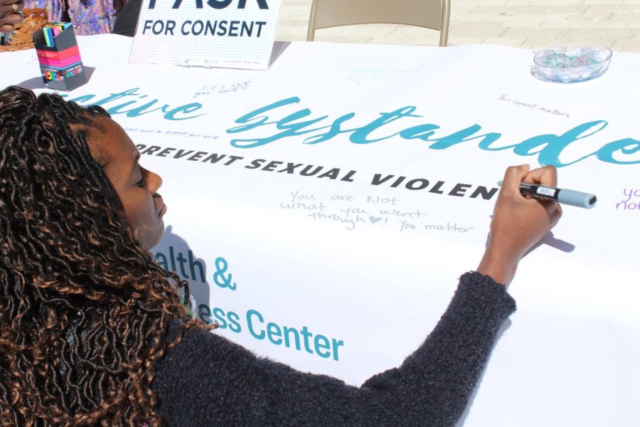 A student writes a supportive message for sexual assault victims on Wednesday. 