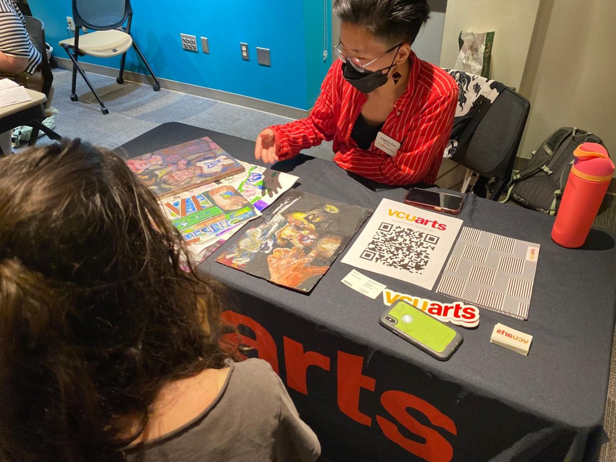 Angelica Kim, an admissions officer for Virginia Commonwealth University, offers feedback on a student's art portfolio at an AACC event on Thursday.