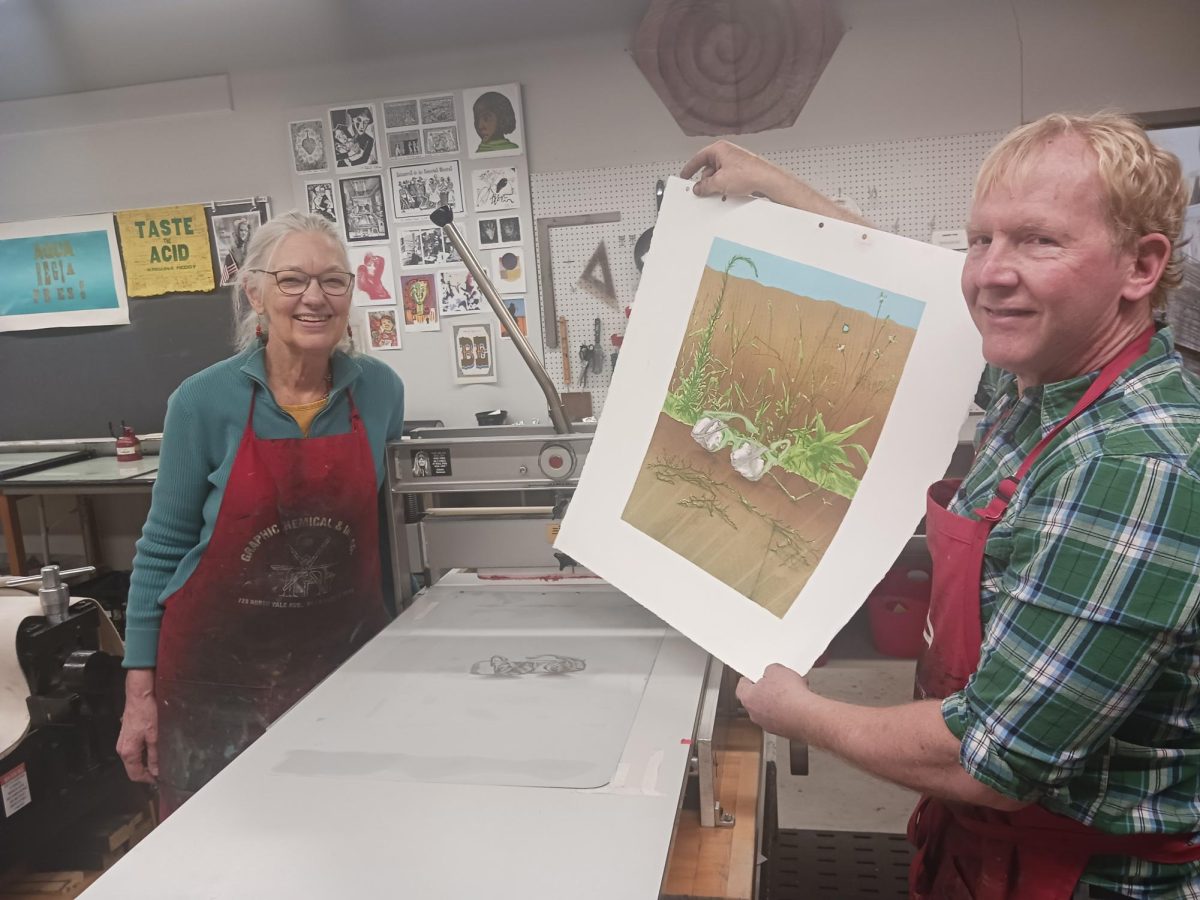 Art professor Chris Mona, right, shows a printmaking piece. Second-year undecided student Sheryl Southwick looks on.