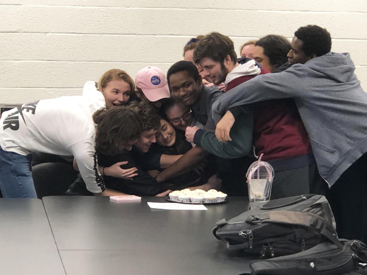 Students should keep in touch with friends and staff after graduation. Shown, friends in a journalism class celebrate a birthday with a group hug.